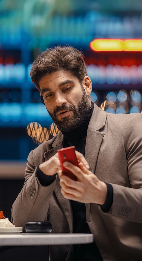 A man with a Vasco Translator E1 in his ear and a Vasco Translator V4 in his hand, demonstrating one-button translation.