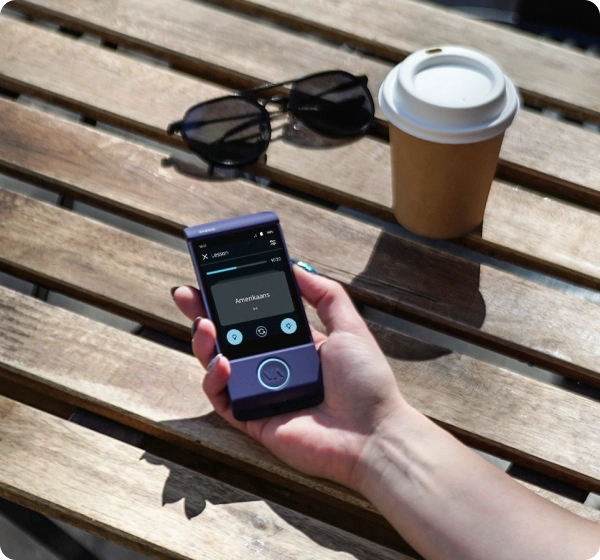 A close-up shot of a hand holding a purple Vasco electronic translator device. The screen displays a text translation from English (UK) to Spanish, showing the word 